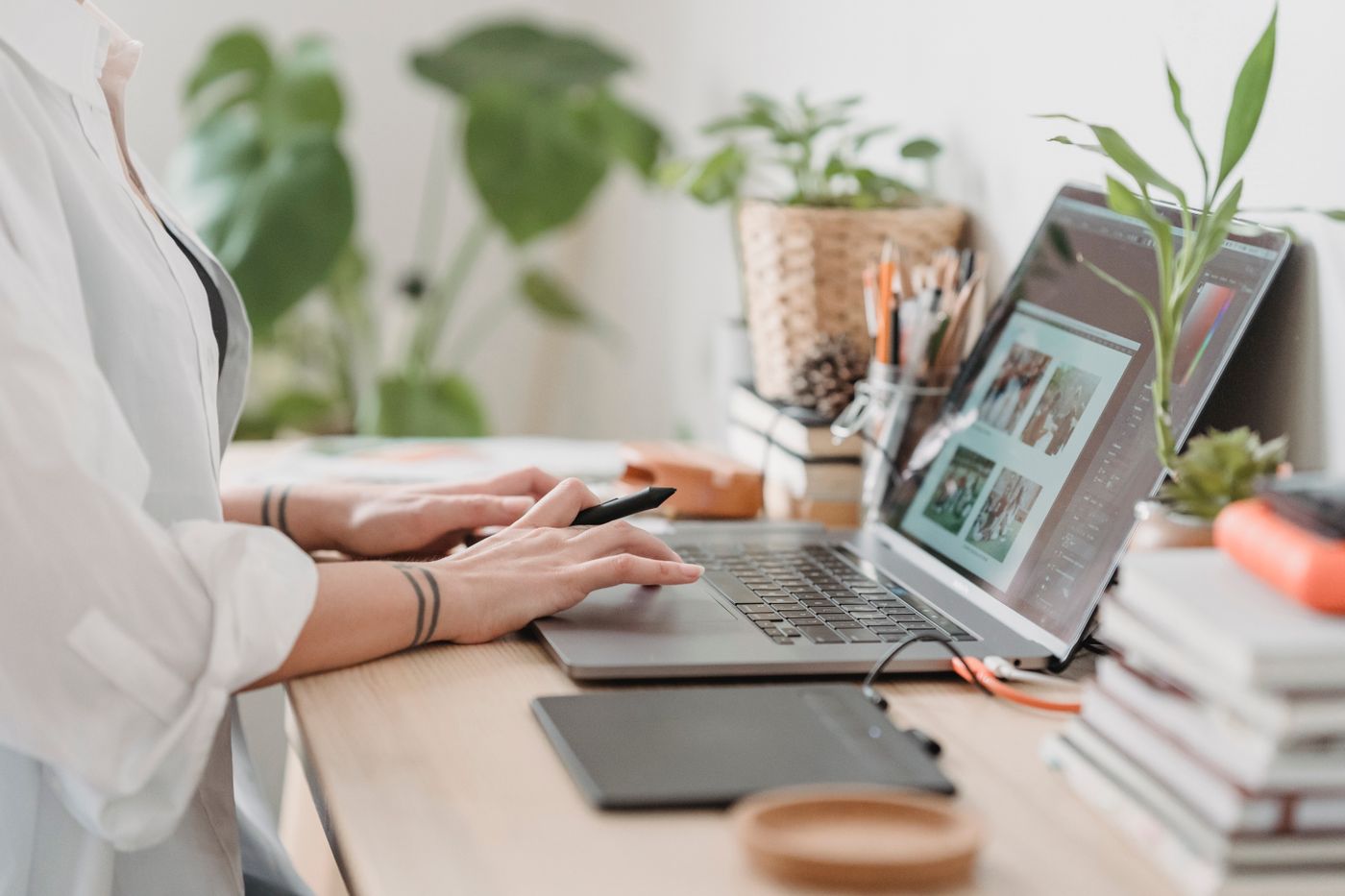 Designer retouching a photo on a laptop beside plants