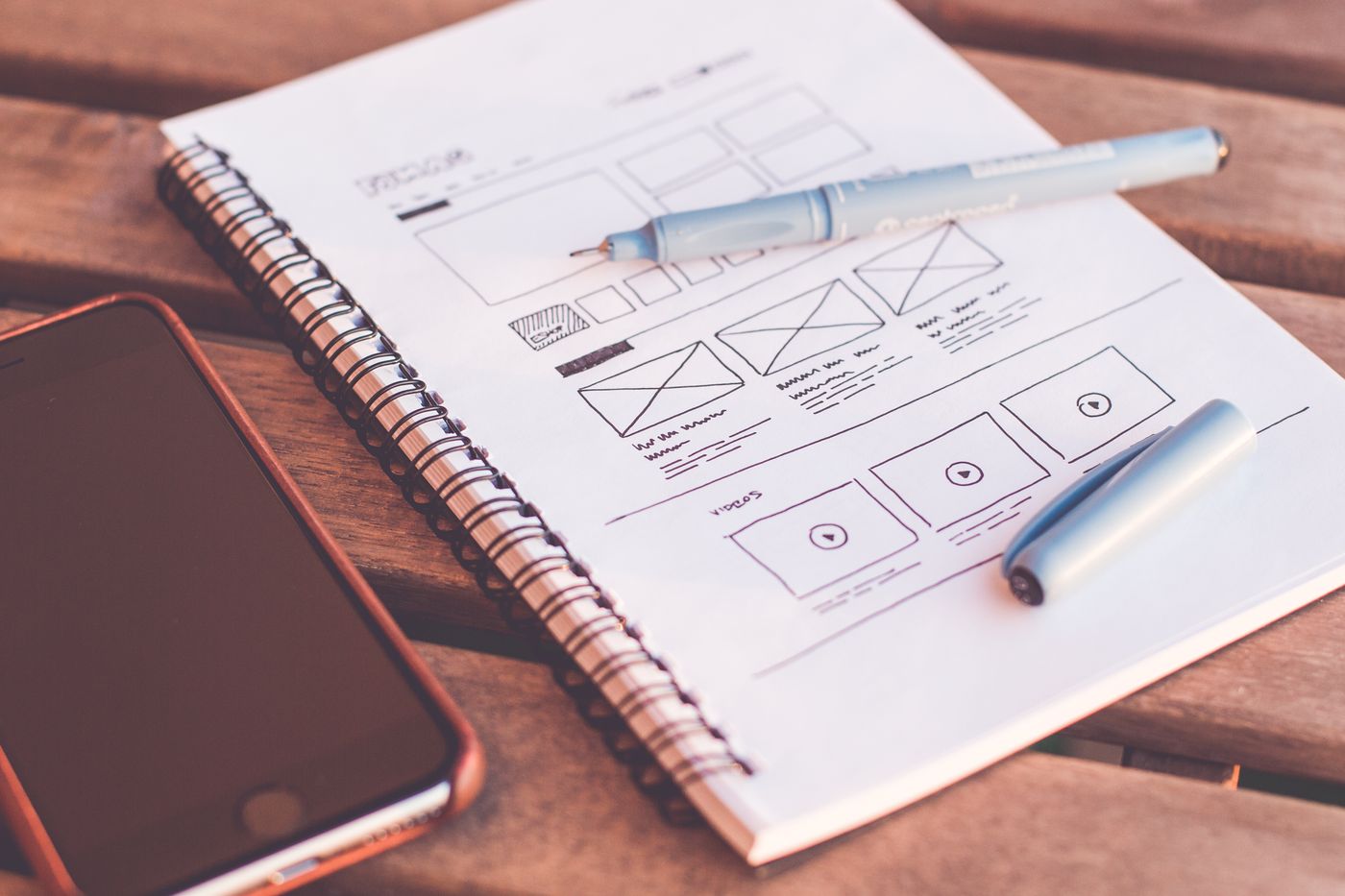 A notebook with wireframe sketches beside a phone